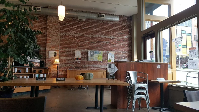 Victrola East Pike café’s brick-walled seating area, communal table and tall windows, photographed in 2022